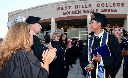 Faculty applaud the new graduates outside after the ceremony.